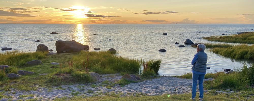 Bild som visar kvinna på strand, solnedgång Kalmarsund
